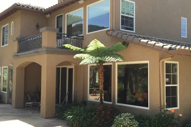 Completed exterior stucco painting on Mediterranean-style Bay Area home front view with balcony and palm trees